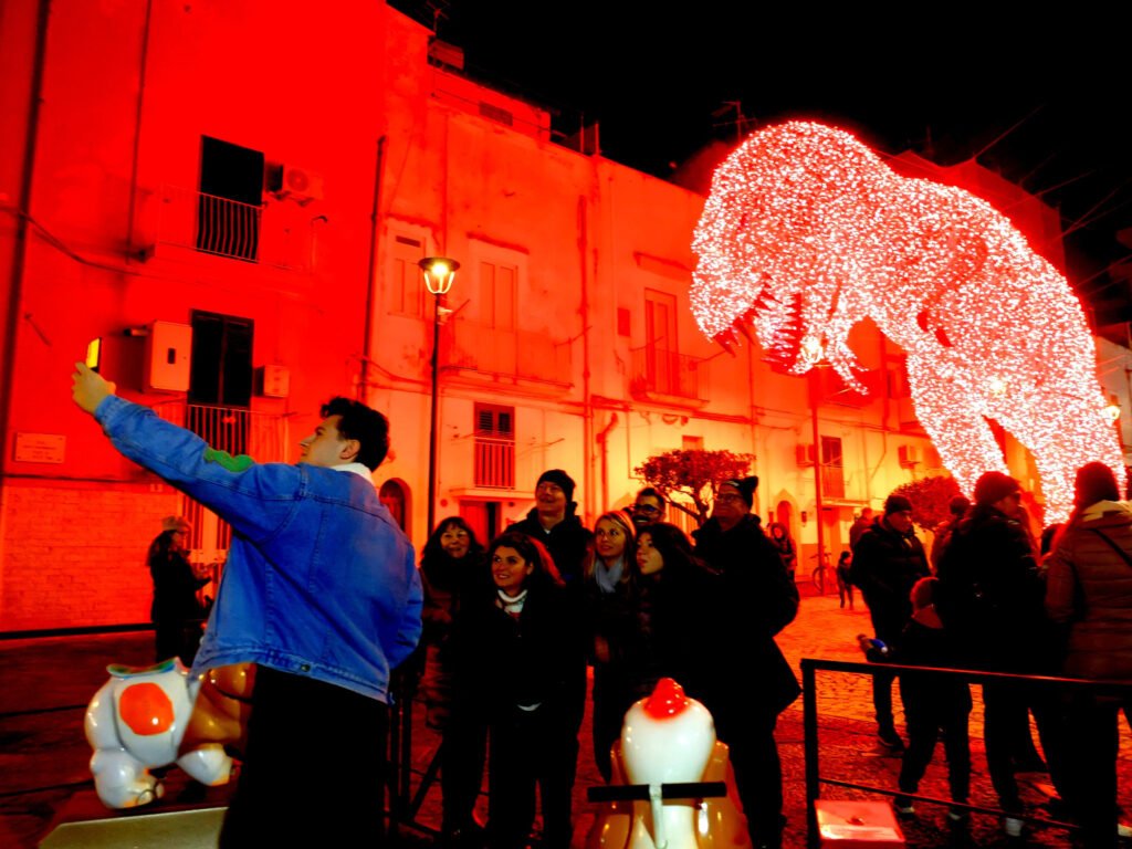 Visitors in front of the illuminated dinosaur at Favole di Luce in Gaeta